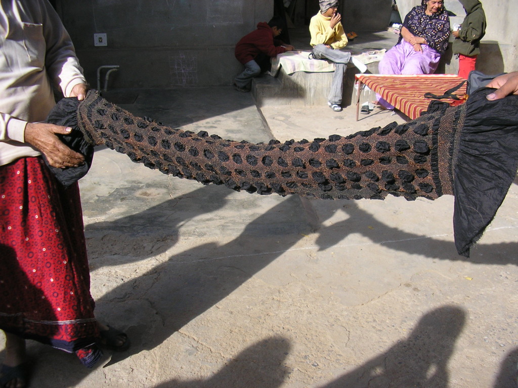 Khatri Alimohamed Isha and his son stretching a bandhani stole to reveal the pattern