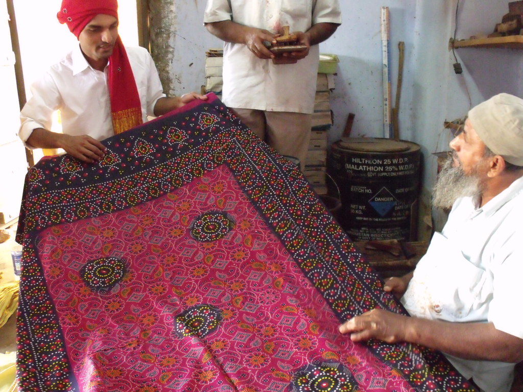 Kuldip admiring a traditional block printed women's odhini (shawl) by Kasimbhai Khatri in Khavda