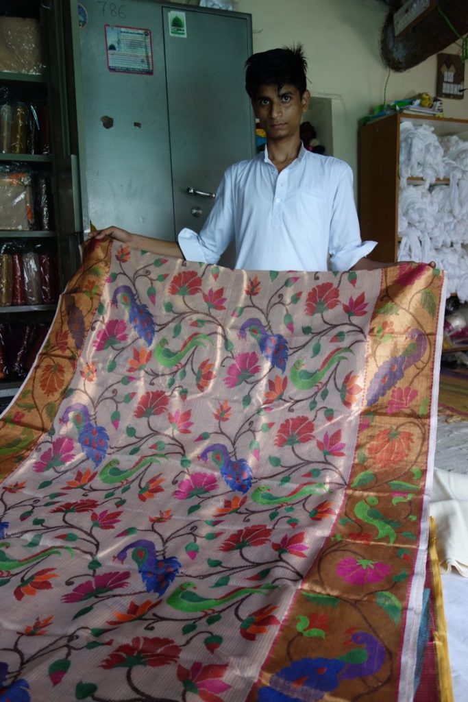 Azgarbhai's son holding a jacquard all-over patterned sari