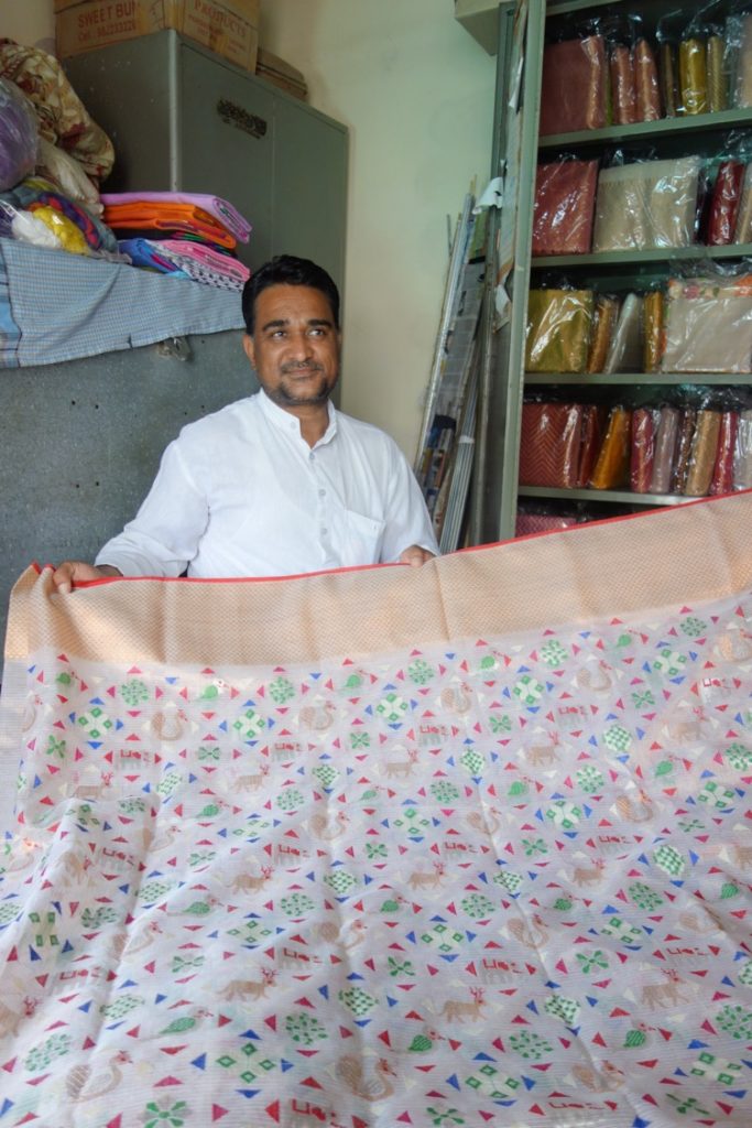 Azgarbhai holding a kota doria sari inspired by the patan patola - evident in the geometric floral and bird motifs